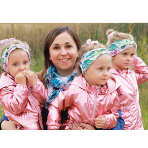 Natural Pharmaceuticals OmegaMarine Junior Mosolygós anyuka három kislánnyal, akik rózsaszín kabátot viselnek.